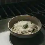 Cremiges Risotto mit Parmesan und frischen Basilikumblättern in einem weißen Teller