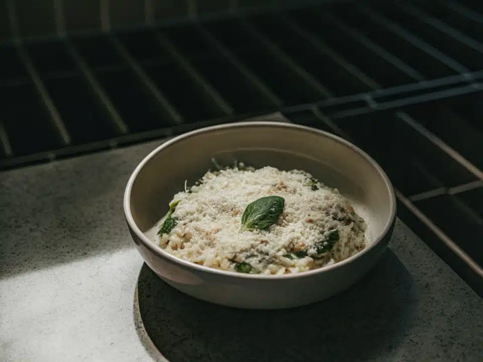 Cremiges Risotto mit Parmesan und frischen Basilikumblättern in einem weißen Teller